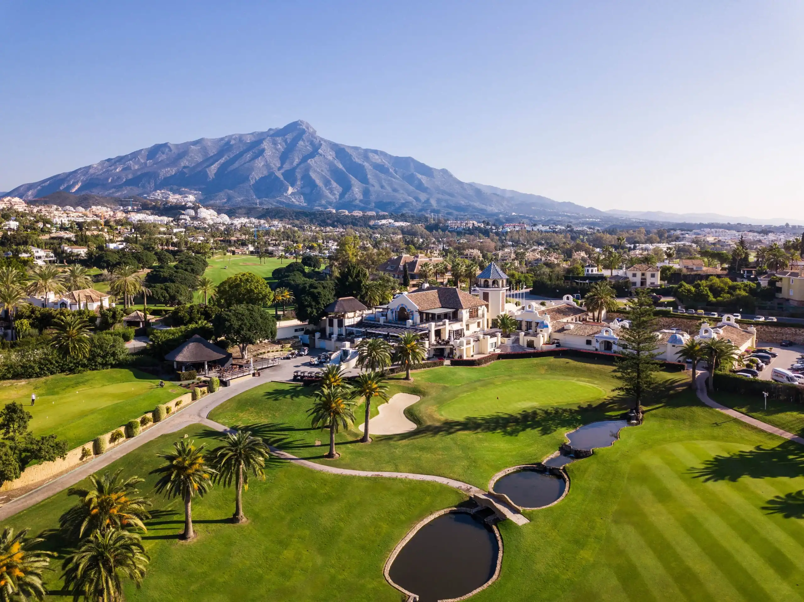Golf course with lush greens and scenic mountain views in Marbella.